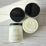 4 jars of body butter with black metal lids on a wooden surface