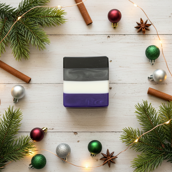 Bar of soap with ace pride flag design surrounded by Christmas decorations on a wooden surface