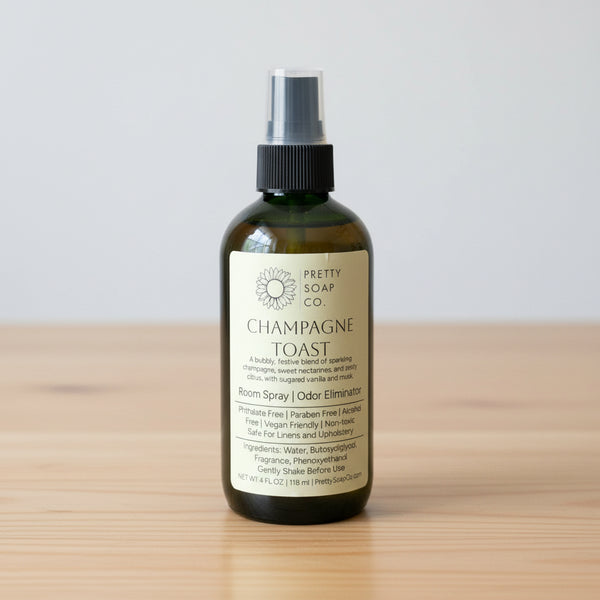 Bottle of 'Champagne Toast' room spray from Pretty Soap Co. on a wooden surface