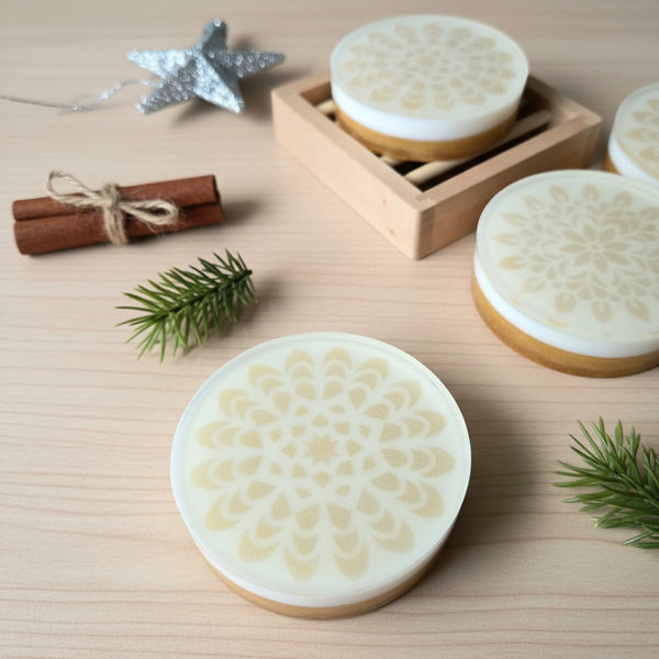 Round white soap with gold mandala design on a wooden surface