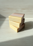 Stack of three soaps on a wooden surface