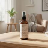 Bottle of 'Cozy Sweater' room spray from Pretty Soap Co. on a wooden surface