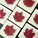 7 soap bars lined up in 3 rows at a diagonal.  White soaps with a red maple leaf in the center.