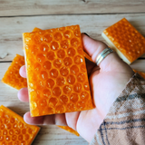 hand holding a soap bar that has honeycomb design on top