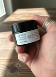 Hand holding a jar of lip scrub with a wooden background