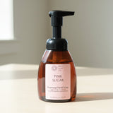 Brown bottle of 'Pink Sugar' foaming hand soap with a pump on a textured gray background