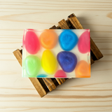 Colorful soap bar with stones in rainbow colors on a wooden surface