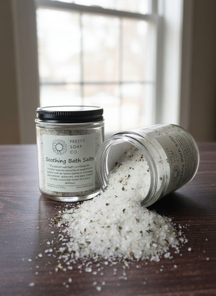 Two jars of bath salts on a wooden surface with some spilled out.