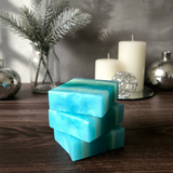 Stack of blue and green striped soap bars on a wooden surface