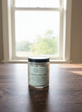 Glass jar of bath salts on a wooden surface.