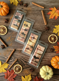 Wax melts in clear packaging on a wooden surface with autumn decorations.