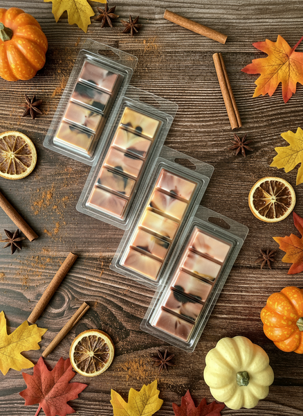 Wax melts in clear packaging on a wooden surface with autumn decorations.