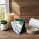 Three stacked soap bars with green and clear layers on a wooden surface