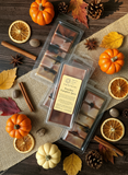 Packaged wax melts with a label on a wooden surface with pumpkins, leaves, and cinnamon sticks.