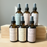 Set of 5 bottles of room spray with labels on a wooden surface