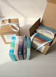Set of colorful soap bars in a cardboard box on a wooden surface