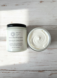 Vanilla Dreams body butter jar with lid open on a wooden surface
